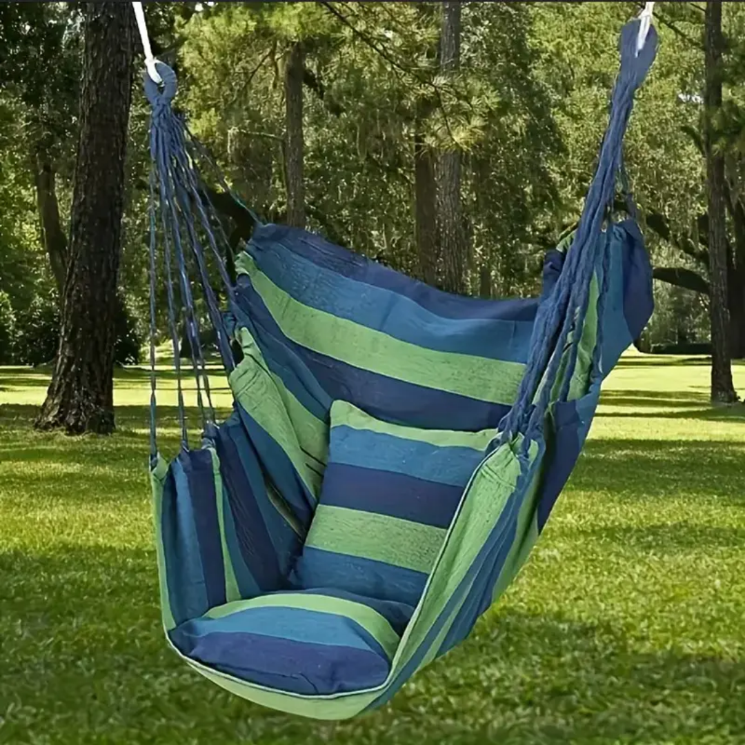 Blue and green striped hammock chair hanging between two trees in a park.